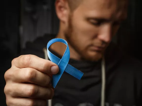 Man holding blue ribbon in forefront of image
