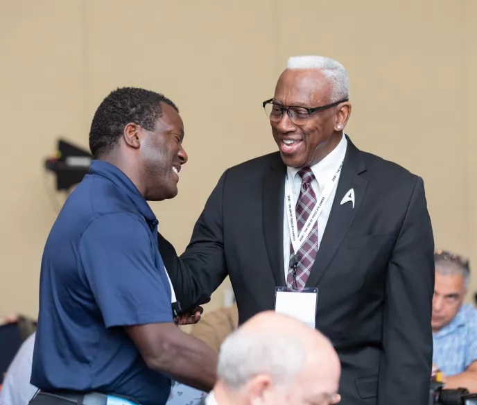 Two African American men shaking hands and smiling