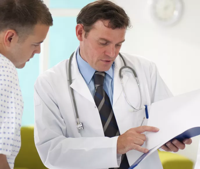 A doctor and a male patient in a gown talking