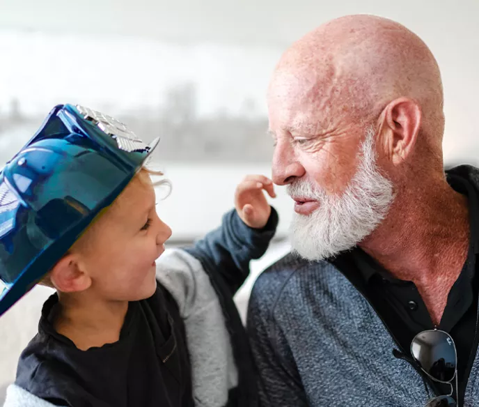 Prostate cancer survivor, Jeff, and his grandson who is wearing a blue firefighter hat