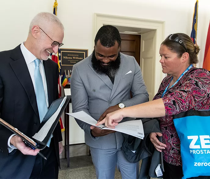 Three advocates looking at papers inside of folders at the Capitol 