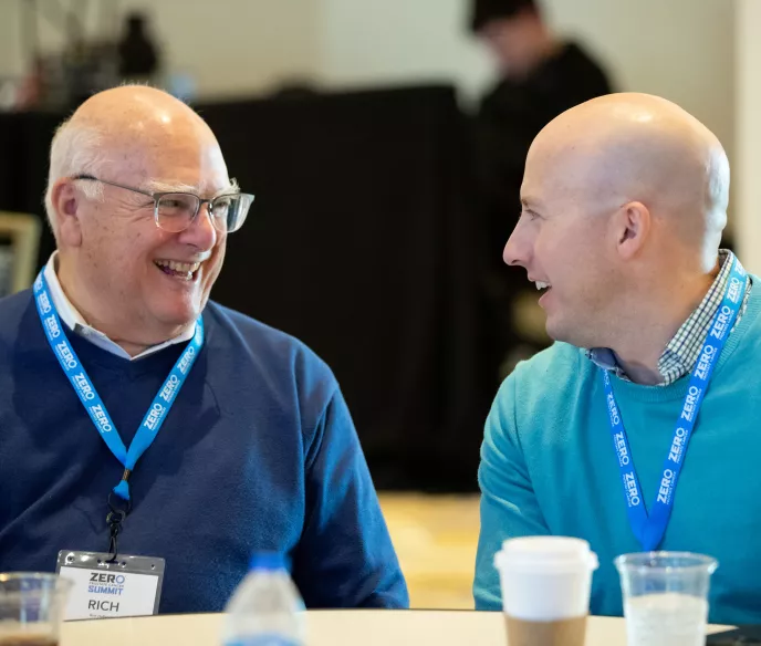 Two bold men in blue sweaters taking at ZERO Prostate Cancer Summit