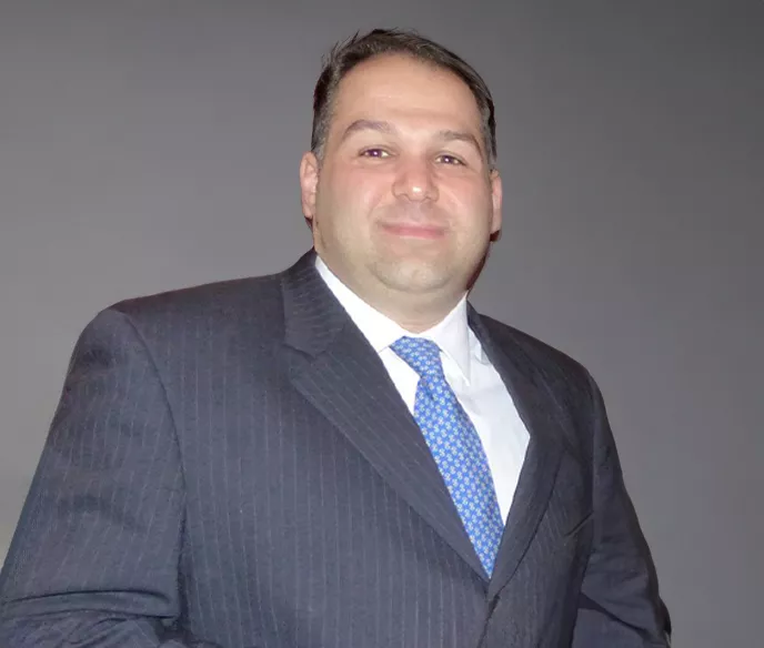 Middle aged white man wearing a blue suit and tie