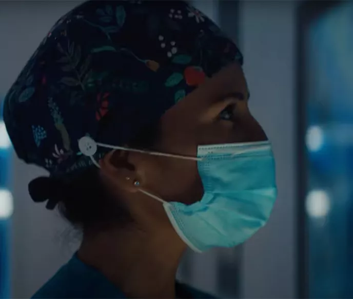 A woman wearing a surgical cap and medical mask standing in a medical facility