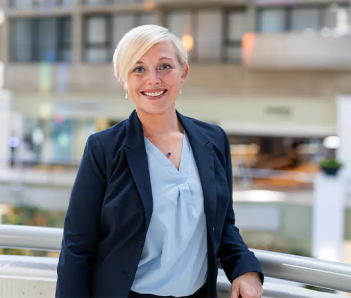 Blonde woman with very short hair wearing a light blue shirt and dark blue blazer