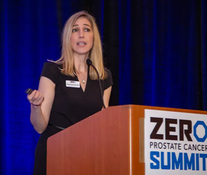 A blonde woman in a black dress behind the podium at Summit
