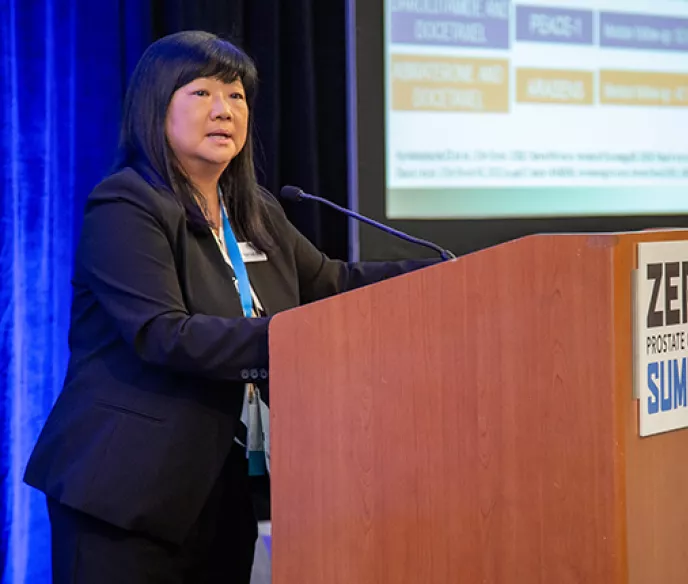 Dr. Elisabeth Heath speaking at a podium at the Summit