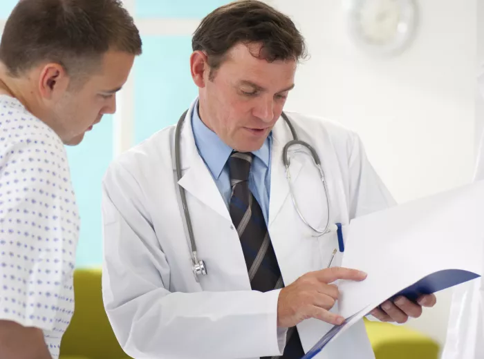 A doctor and a male patient in a gown talking