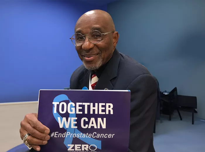 Black man holding a sign that says "Together We Can"