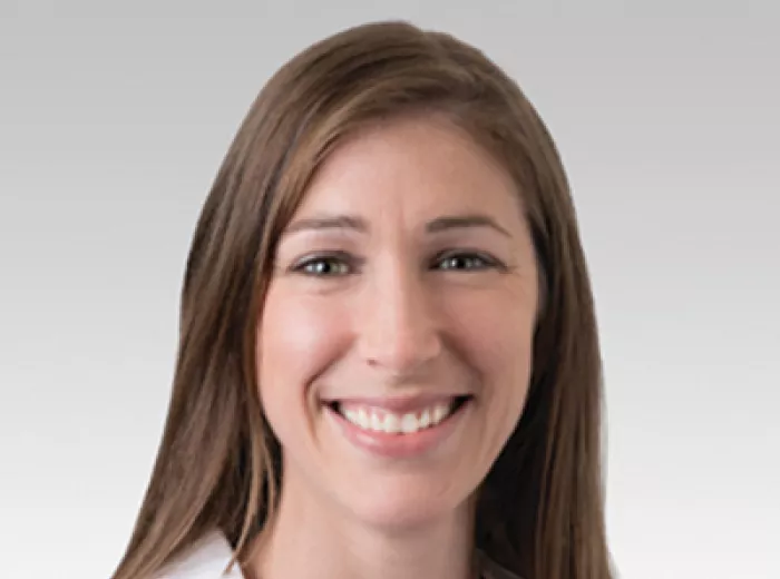 Woman with long brown hair in a white coat, Dr. Alicia Morgans