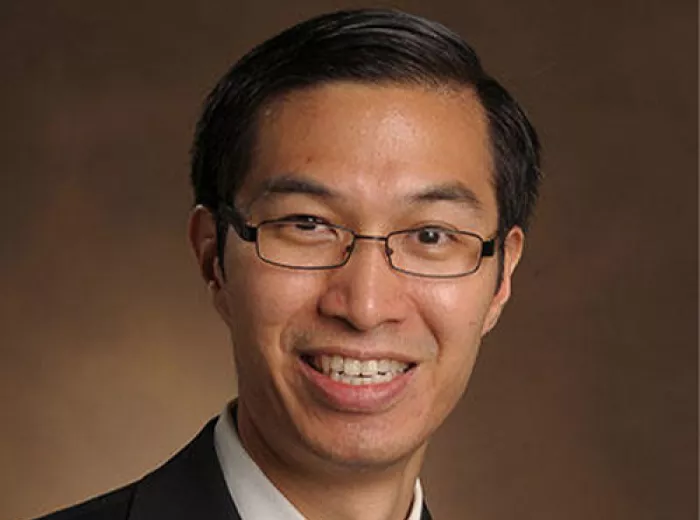 Man of Asian decent wearing a suit and a tie and glasses