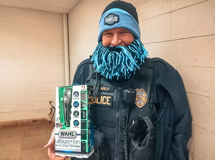 Police officer wearing fake blue beard and holding an electric razor