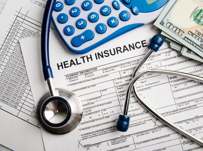 An image of a desk with papers, stethoscope and calculator on it