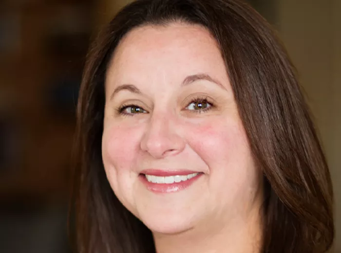 Woman with long dark hair smiling at the camera