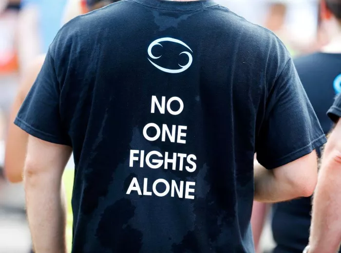 Man wearing a sweaty black t-shirt that says 'No one fights alone'