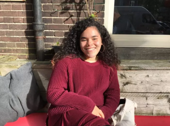 Young woman with long curly hair wearing a maroon sweater, Sam Garcia
