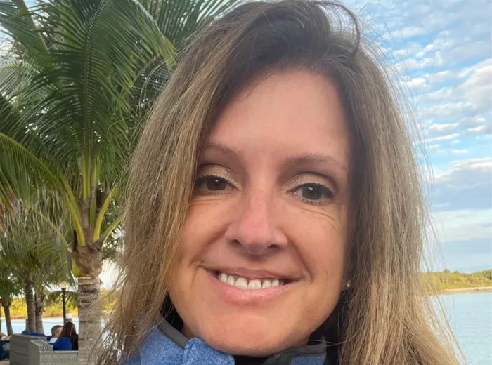 Woman with a long hair wearing a blue fleece jacket at the beach