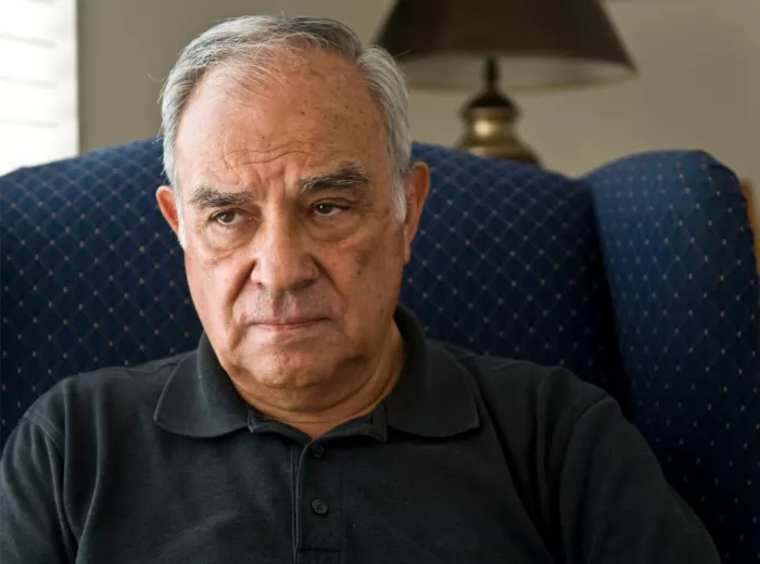 Hispanic man sitting in a living room looking distressed