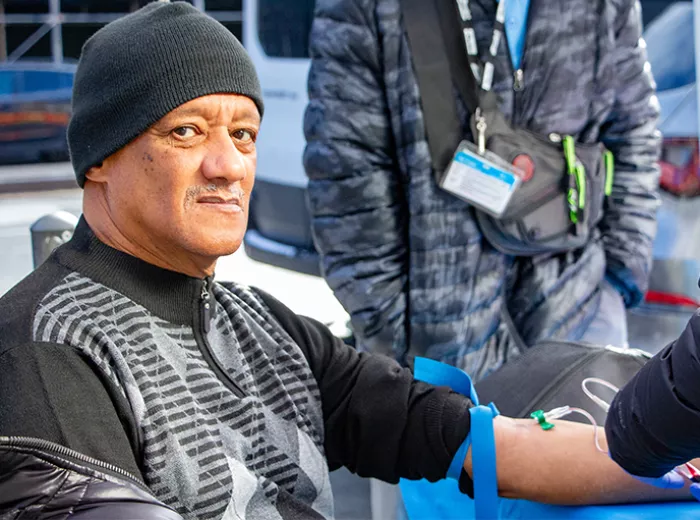 A man getting a PSA blood test, with his sleeve is rolled up and a needle in his arm