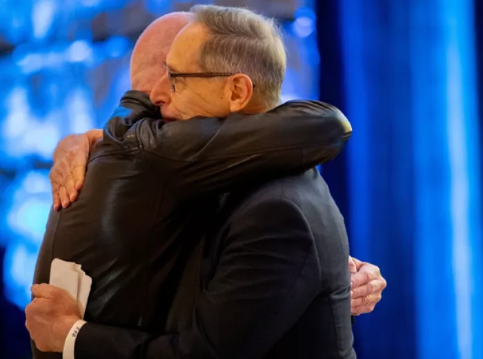 Two men hugging at Bold for Blue Awards wearing black with a blue background