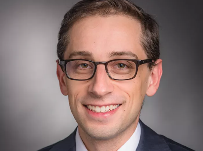 Young man with rectangle glasses posing for a headshot