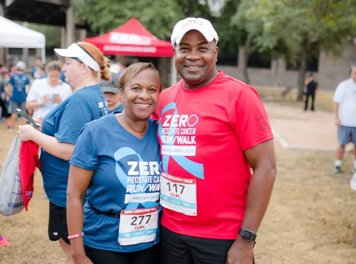 A Black man in a red Run/Walk shirt with a Black woman in a blue Run/Walk shirt
