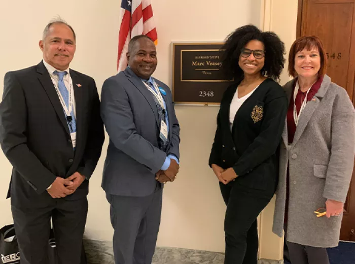 Two men and two women standing outside the Representative from Texas' office in the Capitol building