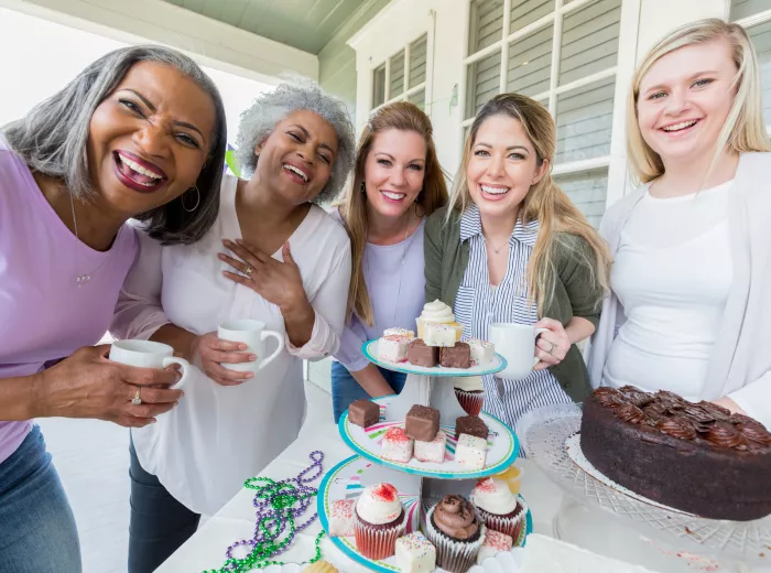 Five women smiling for a picture holding baked goods for a fundraising event