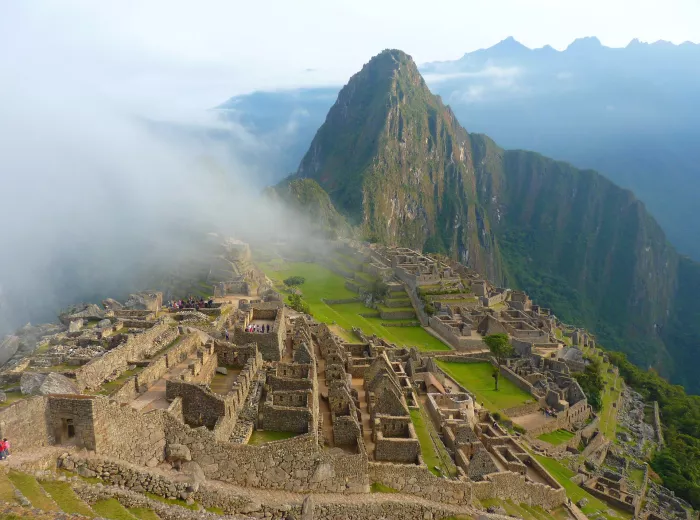 Machu Picchu ruins with misty mountains in the background, showcasing ancient stone structures and terraces.