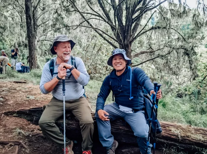 Two men sitting on a log at Kilimanjaro