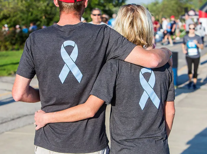 Two people with blue ribbons on the back of their shirts