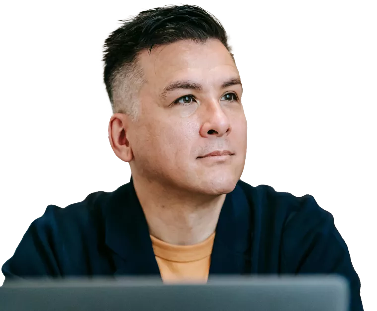 A guy sitting in front of his laptop but looking off into the distance