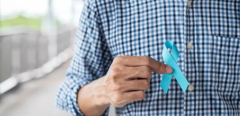 A man holding a blue ribbon for prostate cancer awareness