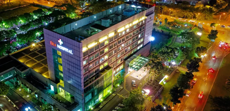 A hospital in a city at night time with many sources of bright colored lights