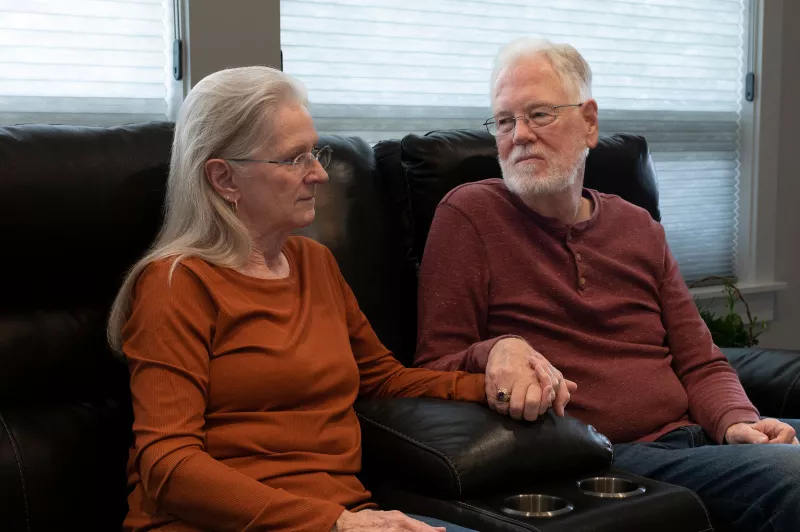 Elderly white couple in a pensive mood and holding hands 