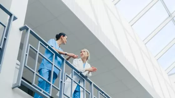 two doctors talking in hospital talking over a railing