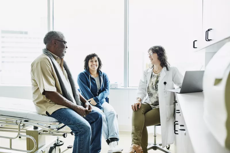 Black male and wife sit in sterile doctors office receiving news
