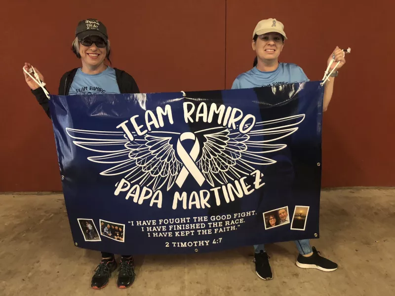 Two women holding up a Team Ramiro Papa Martinez cancer memorial banner