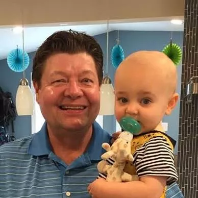 Jim Obert holding a child with a pacifier in its mouth