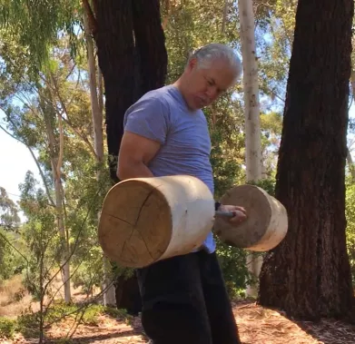 White man lifting handcrafted weights made of out of wood