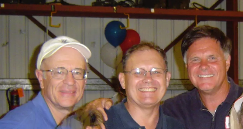 Three men standing in front of one set of red white and blue ballons
