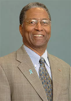 Black man posing in tan suit for company headshot