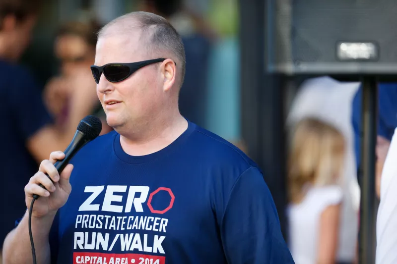 Paul Taylor wearing a ZERO shirt and speaking into the microphone at an event