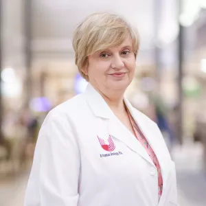 Short haired blonde woman wearing a nurses white coat smiling at the camera