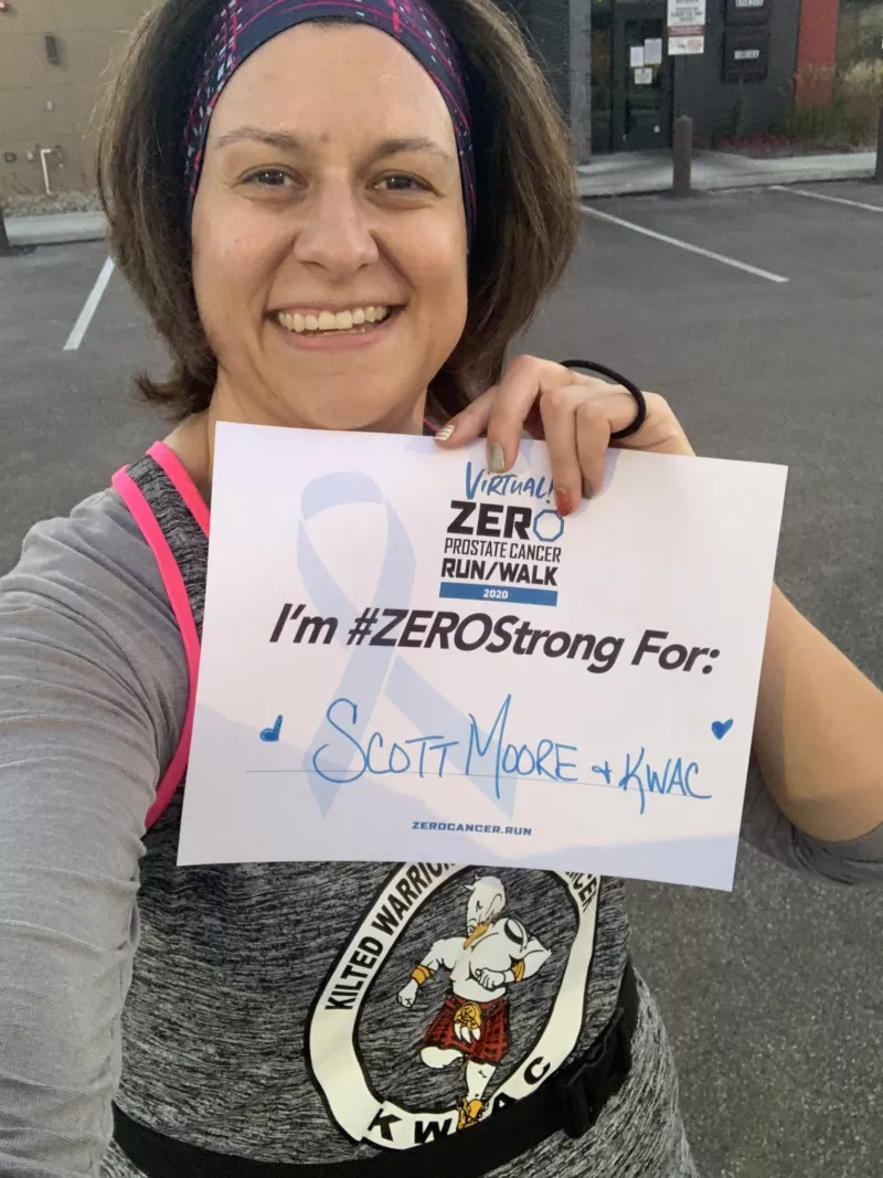 Stephanie Mueller holding up a I'm Zero Strong for sign that says Scott Moore and KWAC