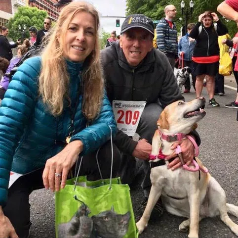 Man and woman with their golden dog at walk or run event