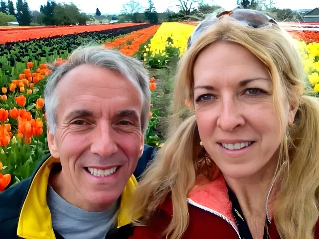 Ted Healy and wife in front of fields of yellow and red flowers