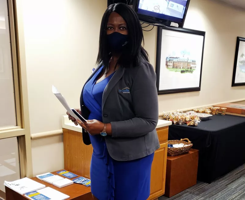 A Broadlawns Medical professional wearing a mask and holding promotional material