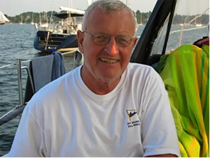 Brad sitting and smiling on a boat out on the water surrounded by land