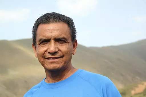 Latin man in blue shirt standing in front of barren mountains